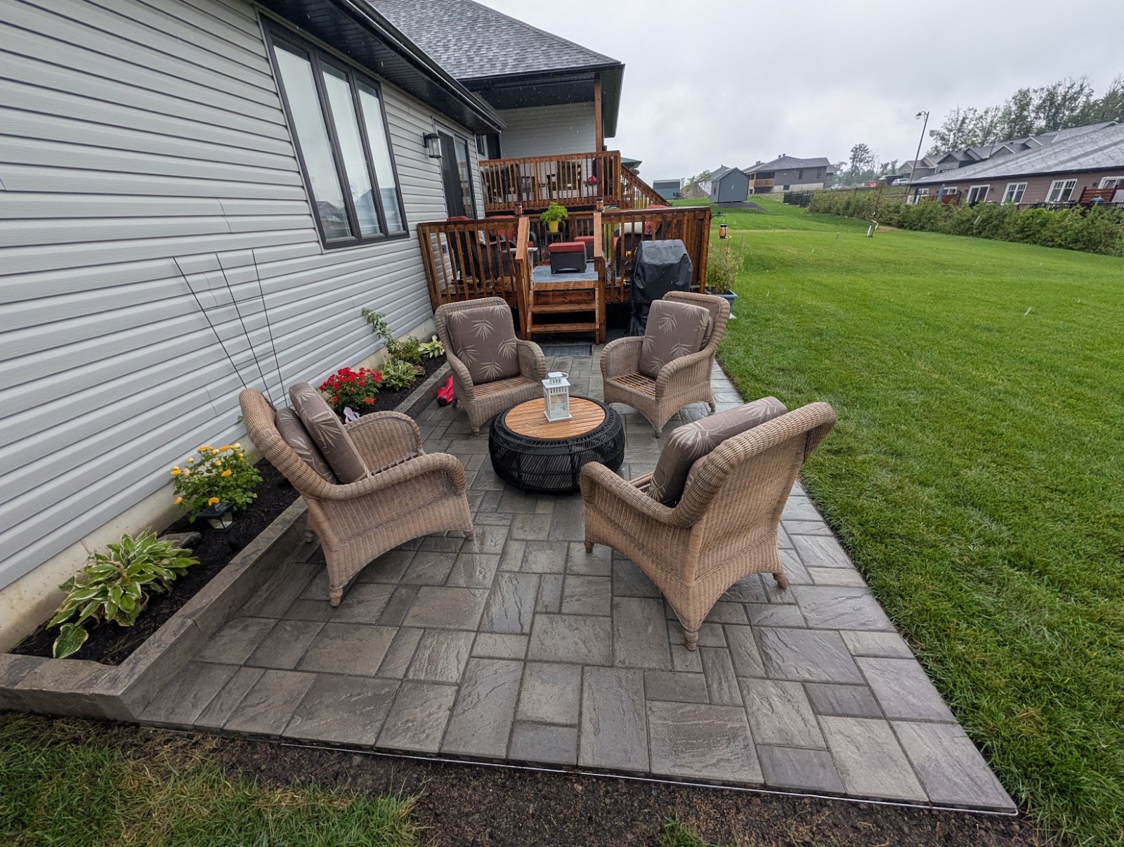 Finished backyard paver patio with table and chairs on a large lawn